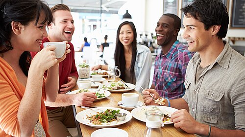 Group of young people sitting in a cafe eating.